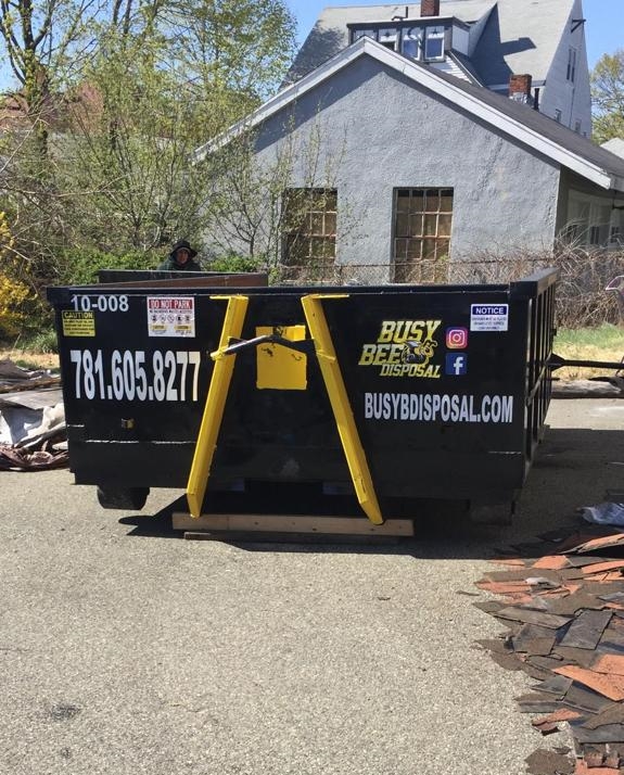 Busy Bee Disposal company dumpster in driveway in front of a house
