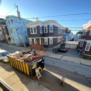 black and yellow dumpster sitting outside in a neighborhood
