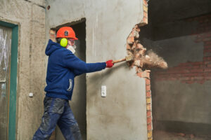 demolition worker hitting a brick wall with a sledgehammer