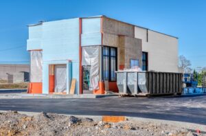 Roll-off dumpster next to unfinished building