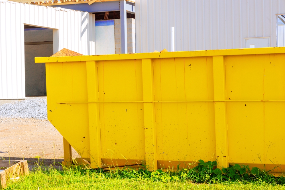 Yellow roll-off dumpster next to construction project