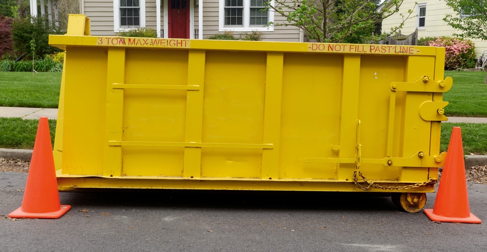 Yellow construction dumpster outside of residential home on the street